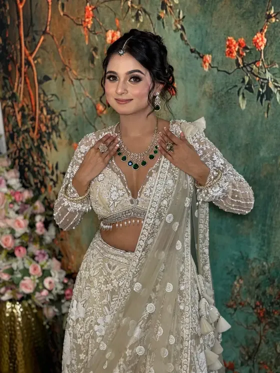 Bride in an ivory lehenga with an emerald necklace