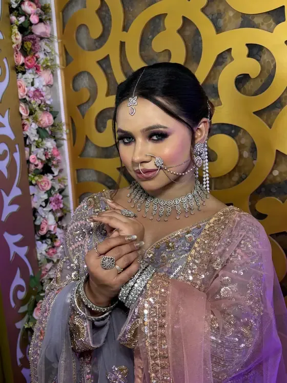 Bride in lilac with a nath and silver jewellery against a gold jaali screen