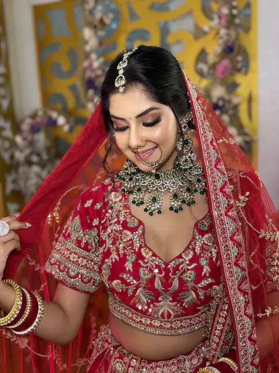 Bride in a red lehenga under a red dupatta, heavy kundan jewellery