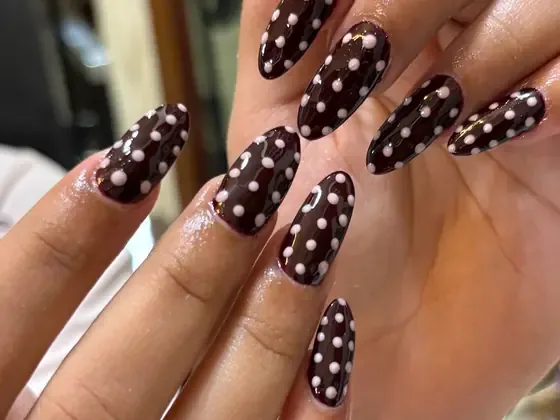 Dark polka dot gel nail art on almond nails