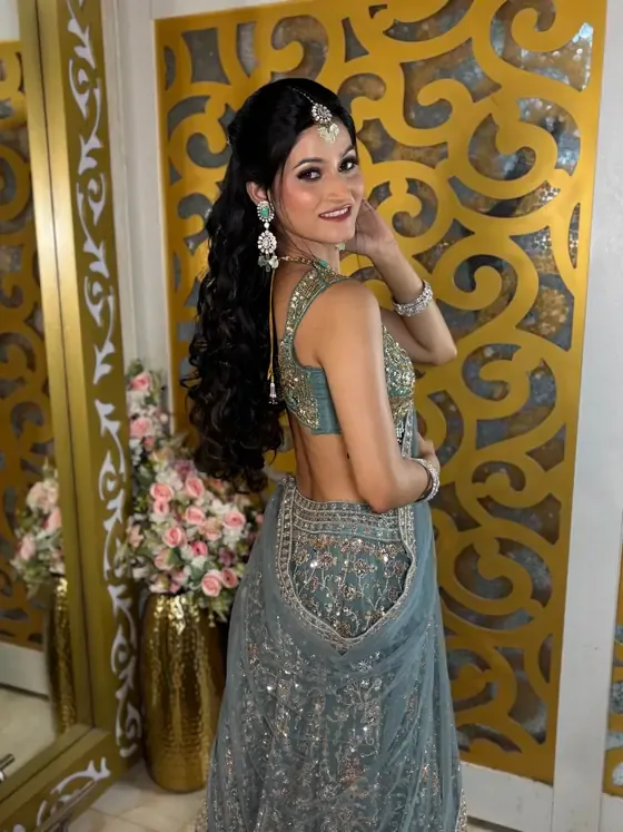 Client in a blue lehenga beside a gold jaali screen